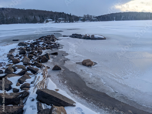 Fotografie Snowy rocky point jutting into a partially frozen lake