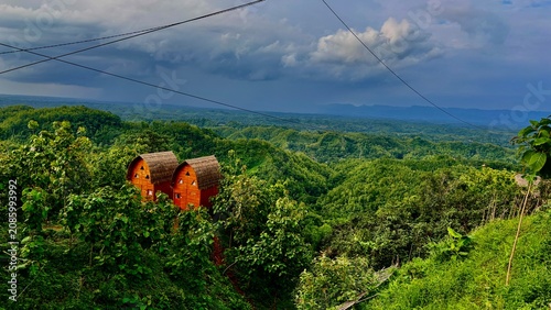 Two Wooden Cabins in Lush Green Hilly Landscape.