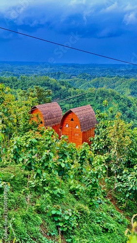 Two Wooden Cabins in Lush Green Hilly Landscape.
