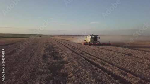 Aerial Drone Panning Shot Following Combine Harvester in Harvested Field at Sunset