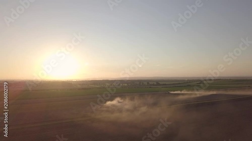 Cinematic Wide Aerial Shot of Dust Rising from Harvest in Distance at Sunset
