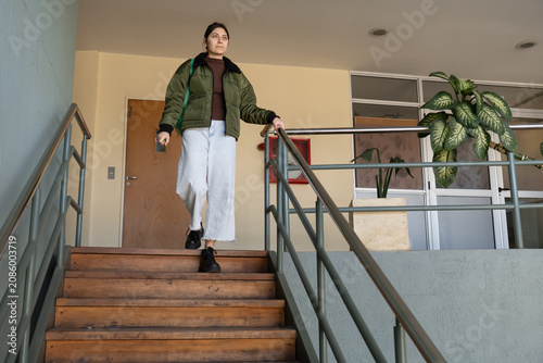 Bild auf Leinwand Young woman descending stairs in institutional building low angle