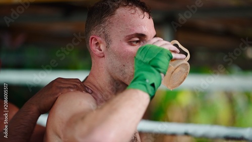 фотографія Muay thai fighter hydrating with water, receiving support after intense training