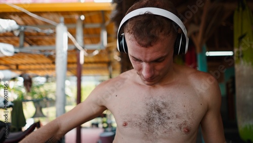 Vászonkép Young fighter concentrating on training, listening to music with headphones