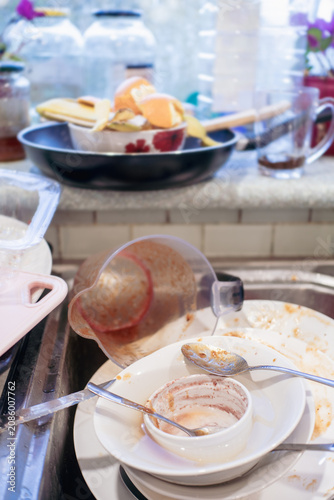 Obraz na plátne Pile of dirty dishes and kitchenware overflowing in a sink after a meal