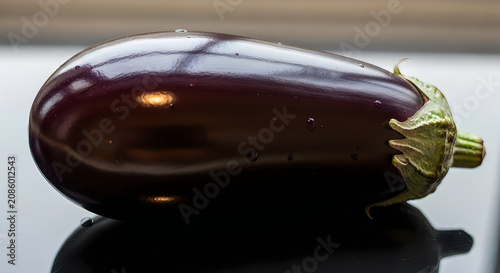 Fresh and glossy purple eggplant on reflective surface