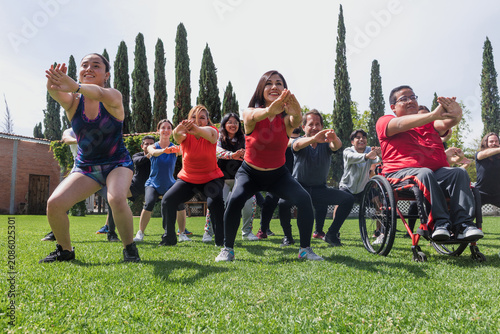 Large Group of Latin sporty multi age people stretching in training class with mexican people in wheelchair outdoors in Mexico Latin America. Diverse hispanic group in inclusion concept