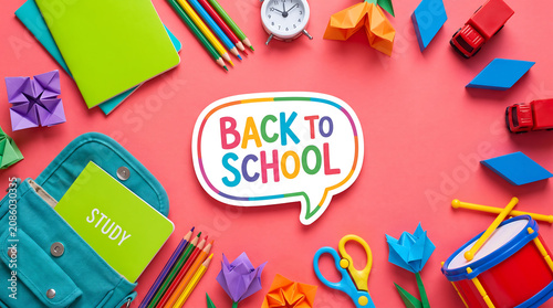 Back to school colorful text on bright coral pink background with open schoolbag notebooks toy trucks