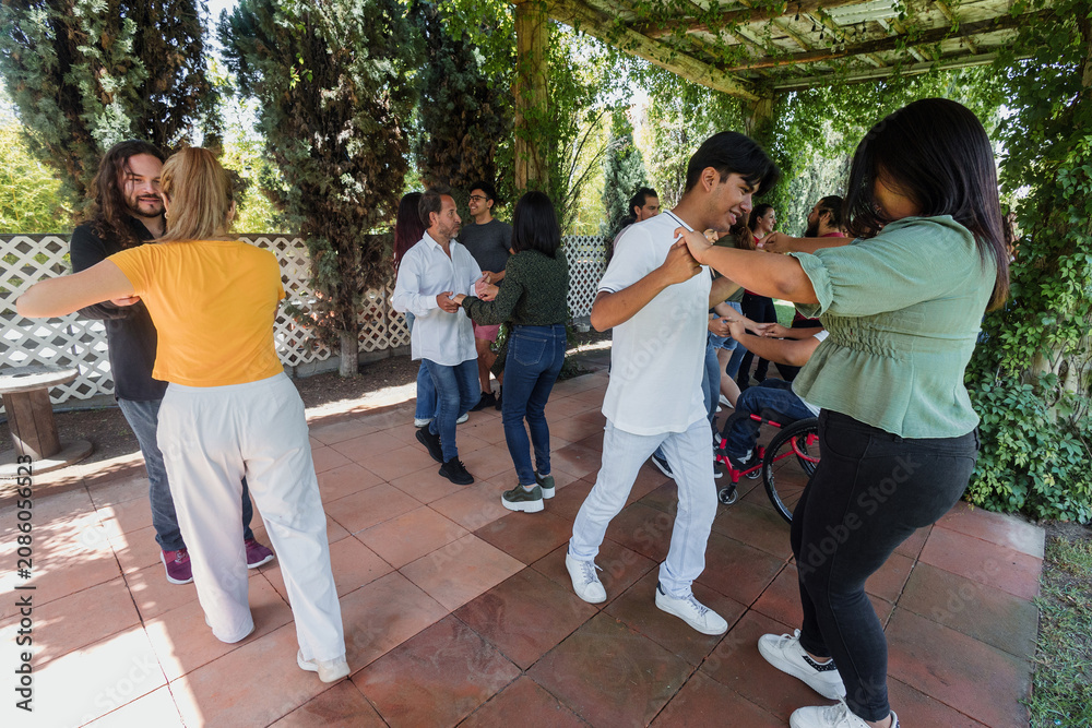 Fototapeta premium Group of latino friends in a salsa dancing class outdoors in Mexico Latin America. Hispanic people moving to the rhythm and having a fun together