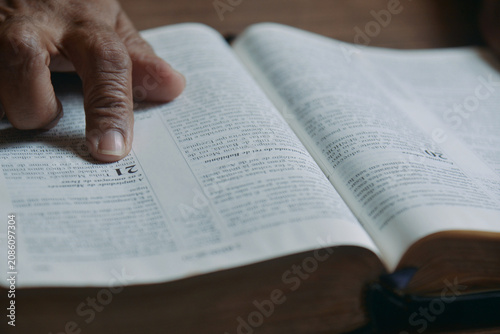 Person reading the Holy Bible with their finger pointing to the biblical passage. Concept of religiosity and reflection.