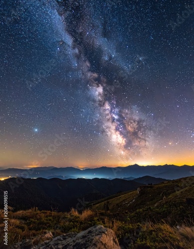 The Milky Way galaxy arcs majestically over a silhouetted mountain range under a starry night sky.