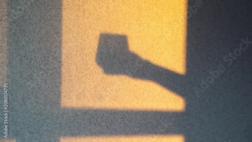 Static Shot Of Human Arm Shadow Extending Across Sunlit Textured Wall In Interior Space During Shifting Afternoon Light.