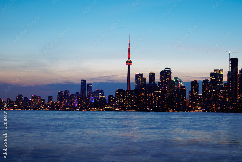 Obraz premium Toronto skyline at dusk with illuminated city lights reflecting on the water, vibrant urban night view. g.