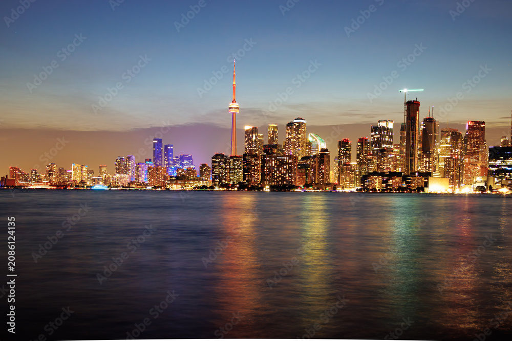Obraz premium Toronto skyline at dusk with illuminated city lights reflecting on the water, vibrant urban night view. g.