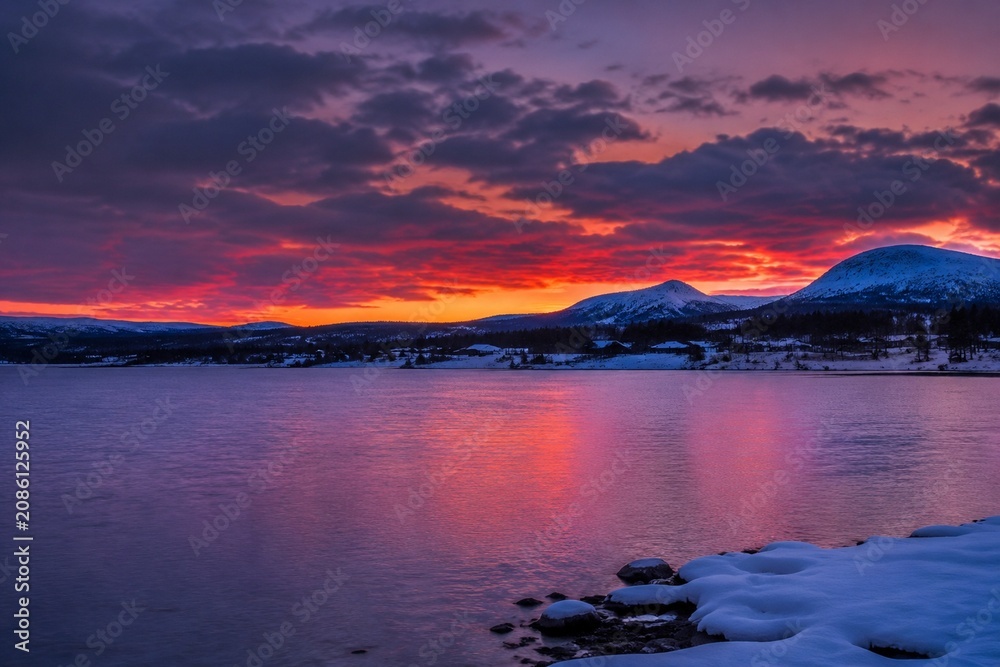 Fototapeta premium Nordic winter lake at dusk with a purple-red sunset sky.