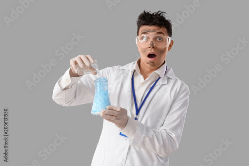 Shocked male chemist making experiment on light background
