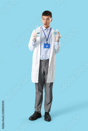 Male chemist with flasks on blue background