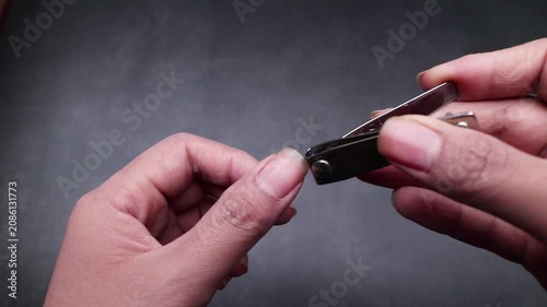 Close up detail of a hand cutting nails showing long, uncut, dry, and dirty fingernails, isolated on gray background.
