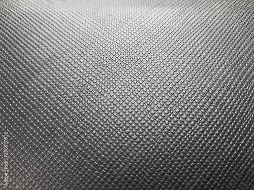 hard surface grid pattern gleams softly under light. Fine, repeating cells form a textured, geometric. Dark gray tones contrast with subtle highlights across the material.