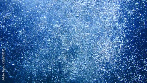 Underwater background with water bubbles and undersea light rays shine. Dark blue ocean surface seen from underwater. Sunbeams and Sea deep or ocean underwater a Abstract background. sunlight Nature.