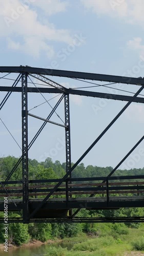 Scenic view of a historic country mill site featuring an old iron and wooden bridge, rustic log cabin, and flowing river on a summer day