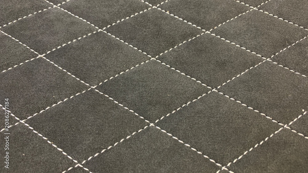 Fototapeta premium Black quilted fabric surface featuring diamond stitching pattern, suitable for upholstery, automotive, and decorative applications