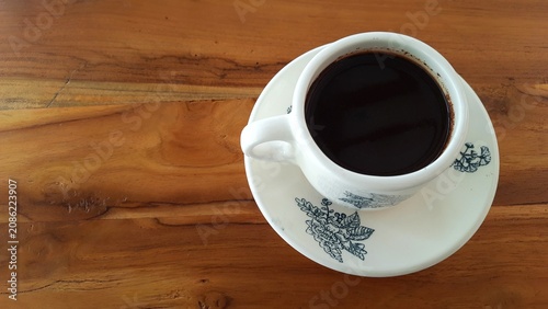 Cup of Black Coffee on Saucer with Floral Pattern on Wooden Table. Business Background