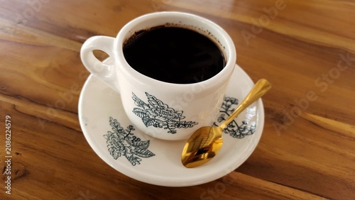 Cup of Black Coffee on Saucer with Floral Pattern on Wooden Table. Business Background