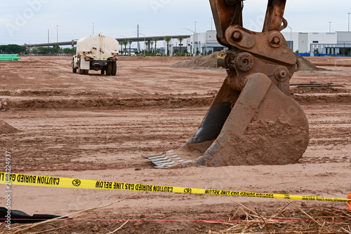 Photos Excavator bucket in the foreground of a large commercial development site with a