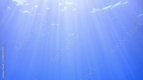 Underwater background with water bubbles and undersea light rays shine. Dark blue ocean surface seen from underwater. Sunbeams and Sea deep or ocean underwater a Abstract background. sunlight Nature.