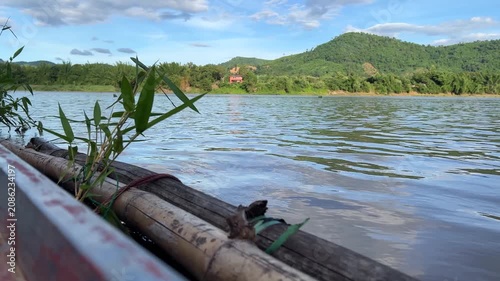 Scenic Mekong River View from Traditional Wooden Boat with Green Mountains and Blue Sky in Southeast Asia