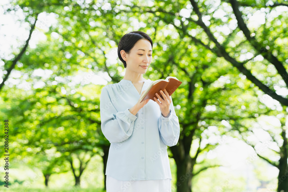 Fototapeta premium 屋外で読書をする若い女性 ライフスタイルイメージ