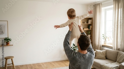 Father playing with baby in living room with couch and window