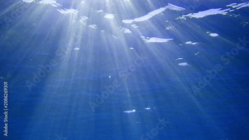 Underwater background with water bubbles and undersea light rays shine. Dark blue ocean surface seen from underwater. Sunbeams and Sea deep or ocean underwater a Abstract background. sunlight Nature.