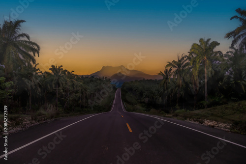 The view along the paved road offers a foreground of the high peaks of Khao Phanom Bencha National Park in Krabi Province, Thailand.