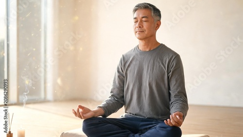 Man meditating in lotus pose with incense and candle for mindfulness and mental health practice