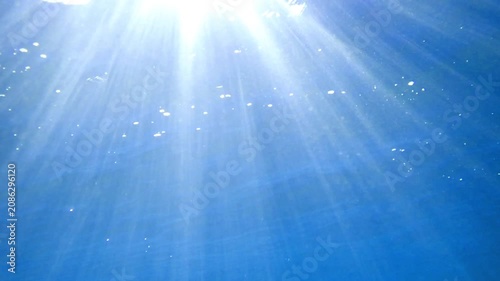 Ocean blue underwater with sunrays, Underwater Sea Deep Water Abstract Sunshine, sea wave , clean waters in summer time, Natural underwater seascape, sand on ocean floor and water surface sunlight.