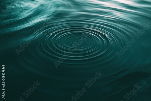 Circular water ripples spreading dark green calm water surface. Peaceful liquid wave pattern concentric circles serene natural