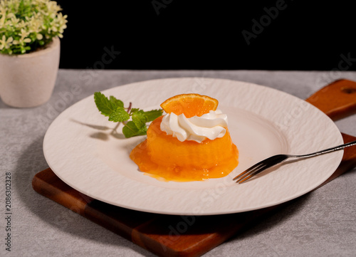 Orange Jelly Dessert with Whipped Cream and Fresh Orange Slice on White Plate,perfect for bakery, café, restaurant, and sweet treat concepts.
