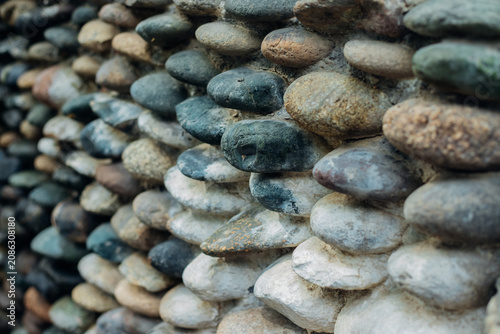 Bild auf Leinwand Background with the texture of a stone wall made of pebbles