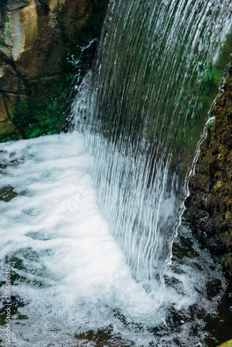 A small decorative waterfall in the city park. Clean, refreshing water.