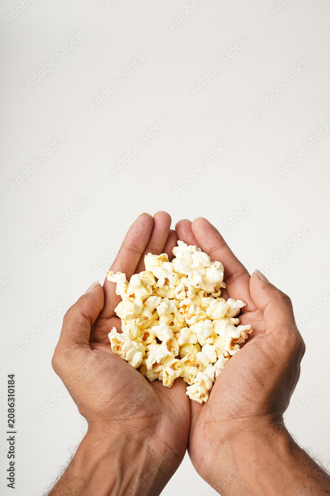Obraz premium close up of hand holding popcorn on white background