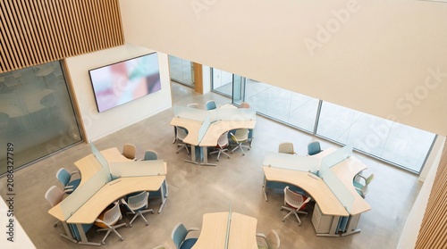 Aerial view of modern open plan office with ergonomic curved desks and collaborative workstations in bright contemporary corporate interior design space.