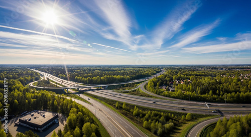 Wide aerial view of highway interchange under bright sun and blue sky