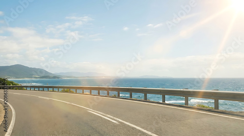 Coastal highway curving alongside blue ocean under bright sun