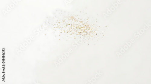 Scattered small specks on a clean white background captured in a minimalist studio style
