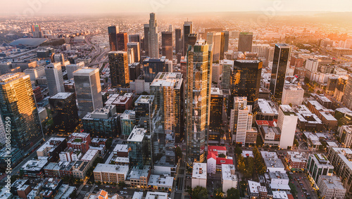 Aerial cityscape at sunset, modern skyscrapers, urban sprawl, golden hour light
