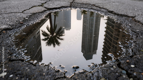 City skyline reflection in a puddle on cracked asphalt pavement