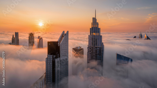 Cityscape Amidst Foggy Sunrise Over Clouds – Modern Architecture