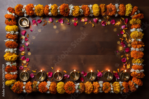 Diwali festival background with marigold flower frame, traditional oil lamps on wooden table, festive floral border for greeting cards